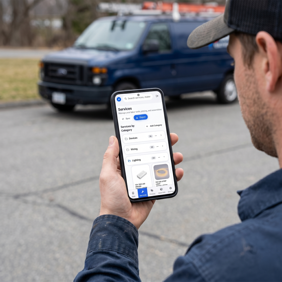 Electrician looking at The Going Rate app scree while standing outside.
